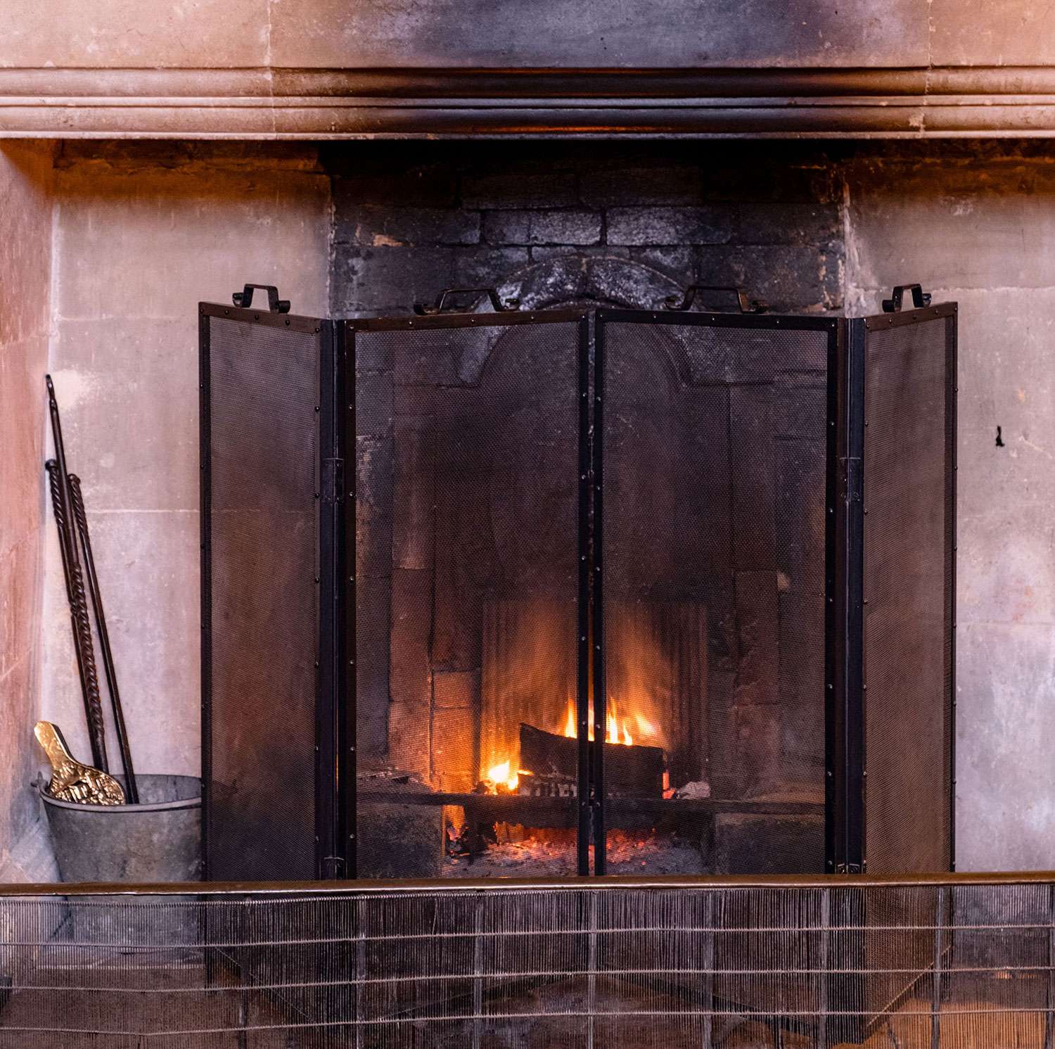 Fireplace with a burning fire behind a screen